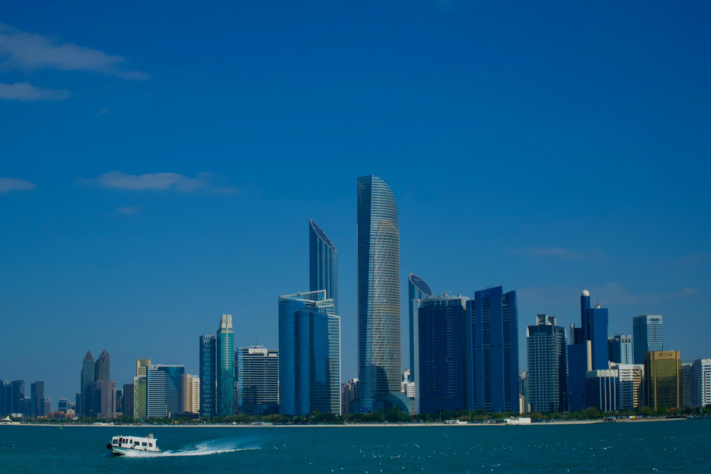Modern towers rising above a blue sea with a boat