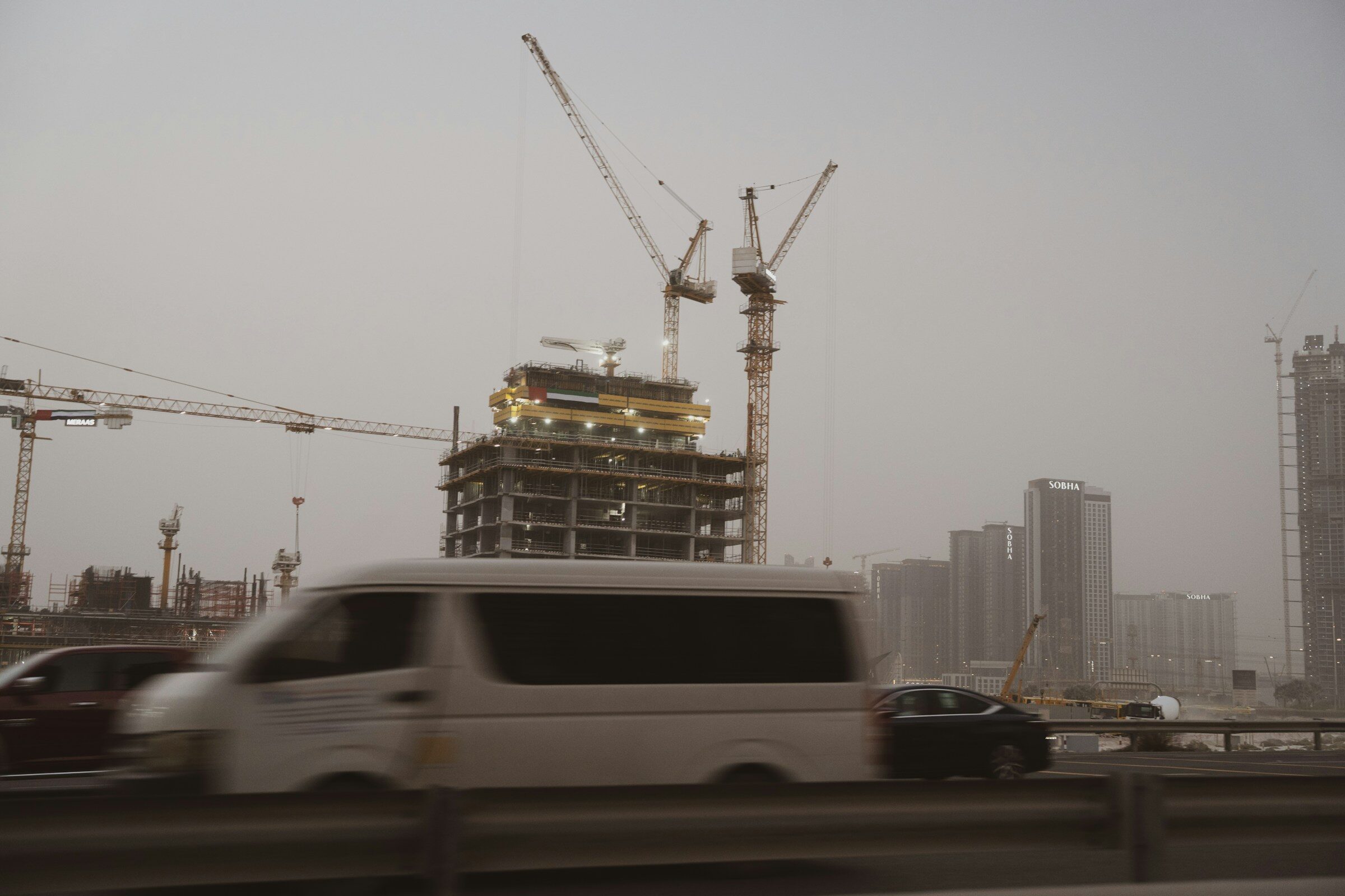 Construction cranes towering over a city skyline