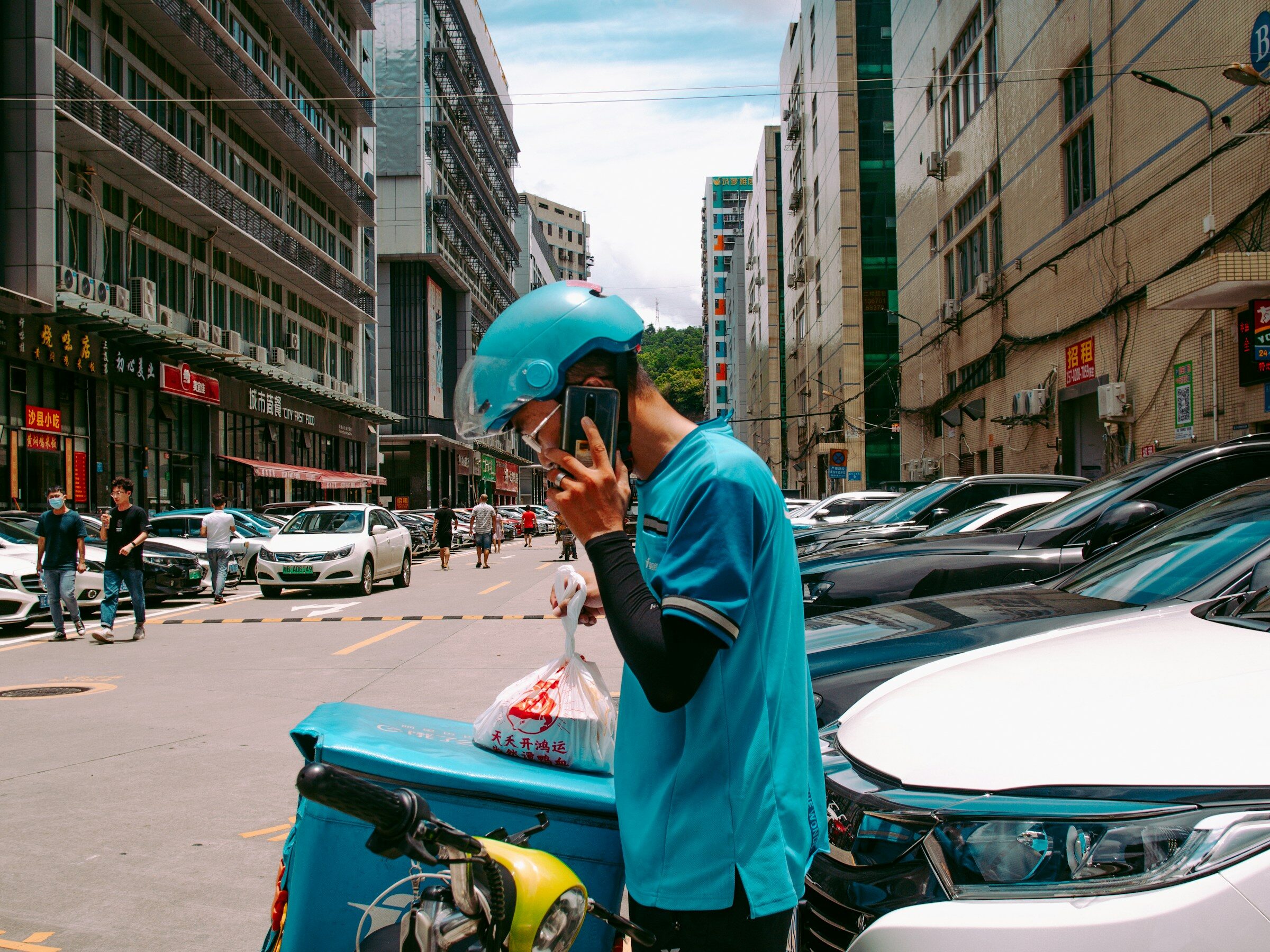 A delivery worker in blue uniform on a scooter