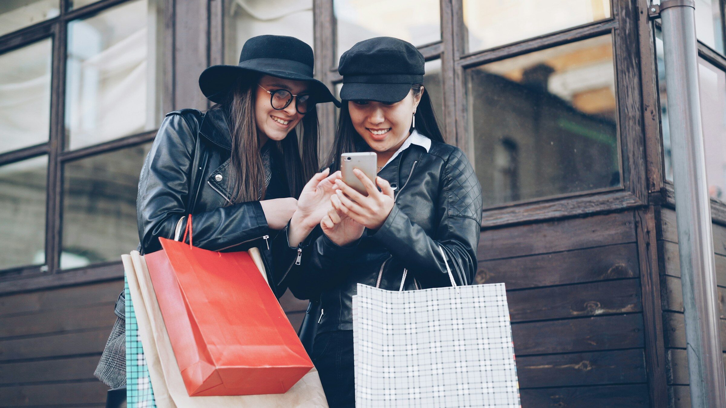 Two women with a smartphone and shopping bags