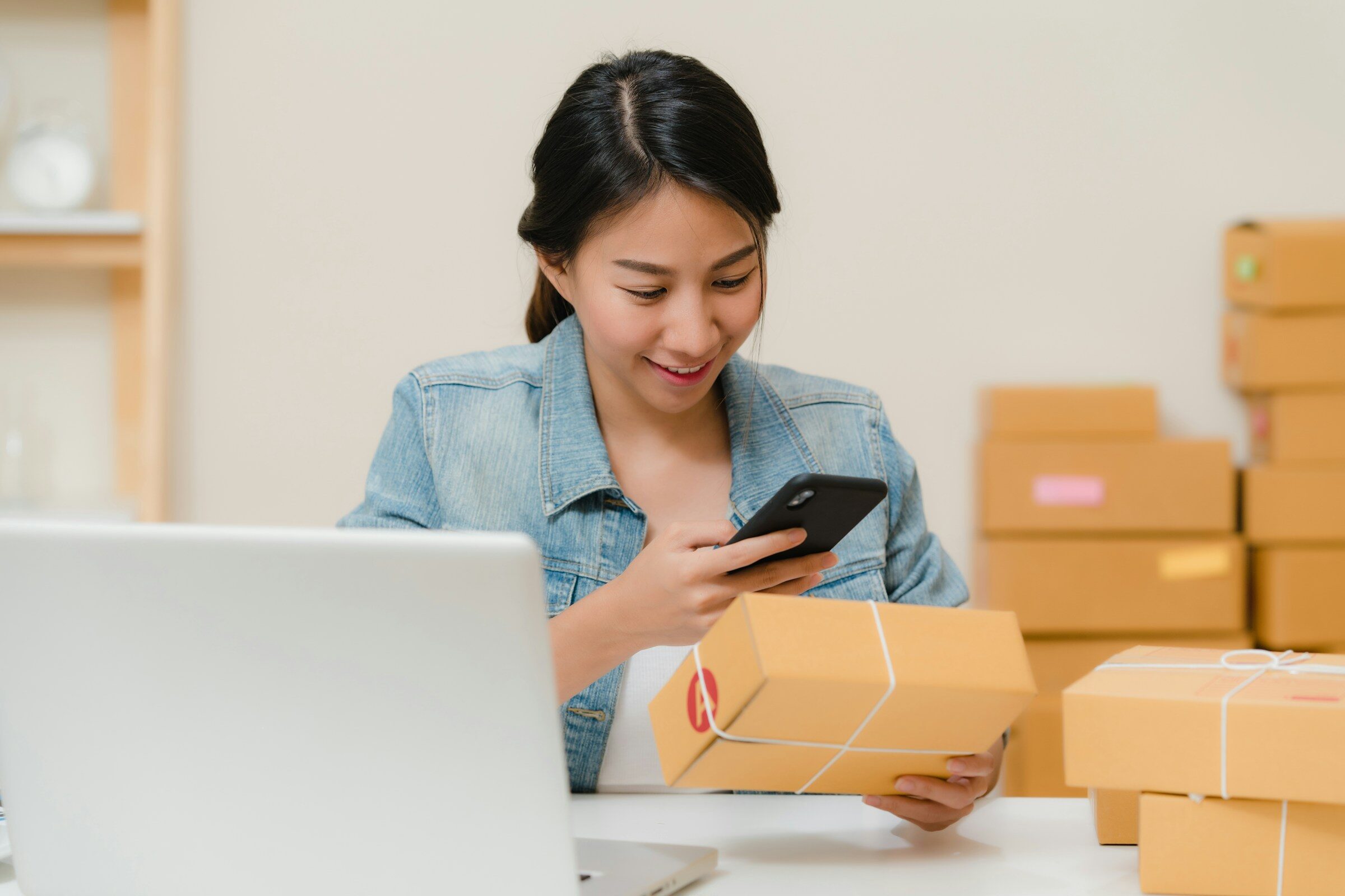 A woman checking a parcel beside her laptop