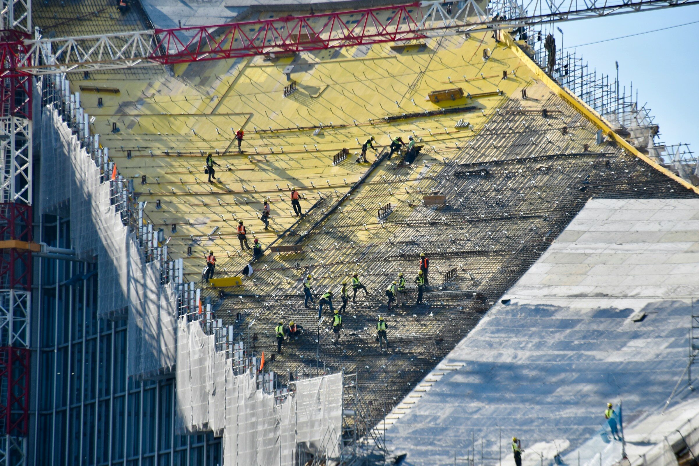 Workers on a large construction site with yellow sheeting