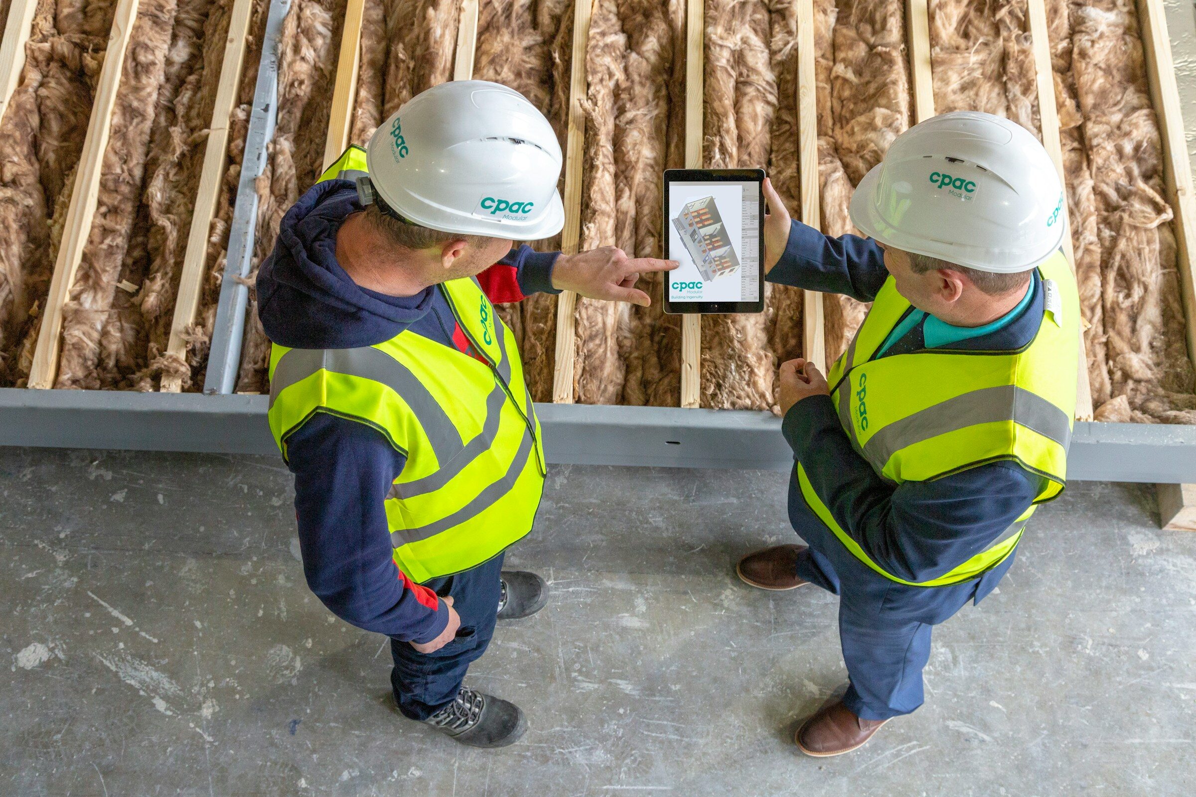 Two construction workers reviewing plans on a tablet