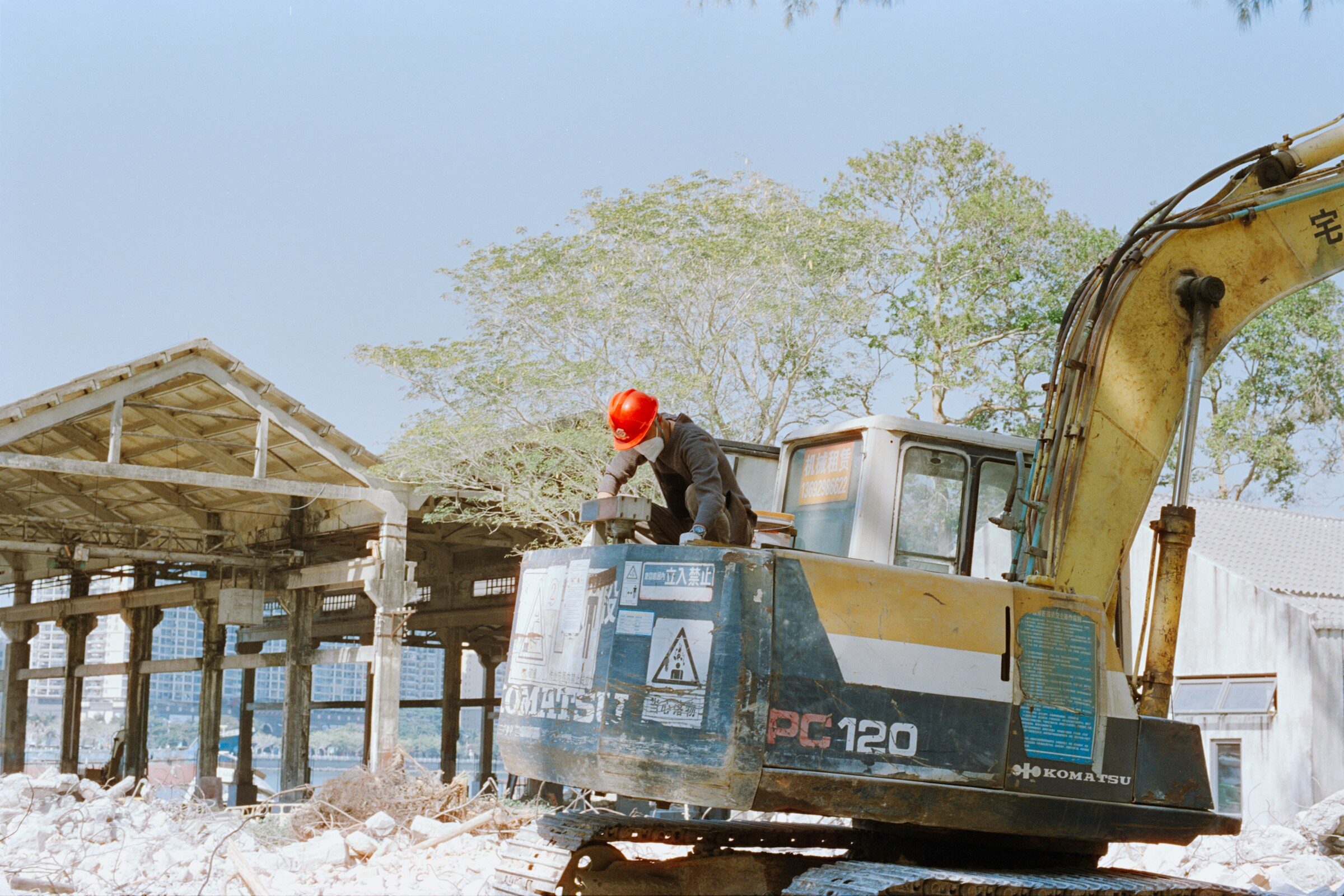 A worker in a hard hat beside an excavator
