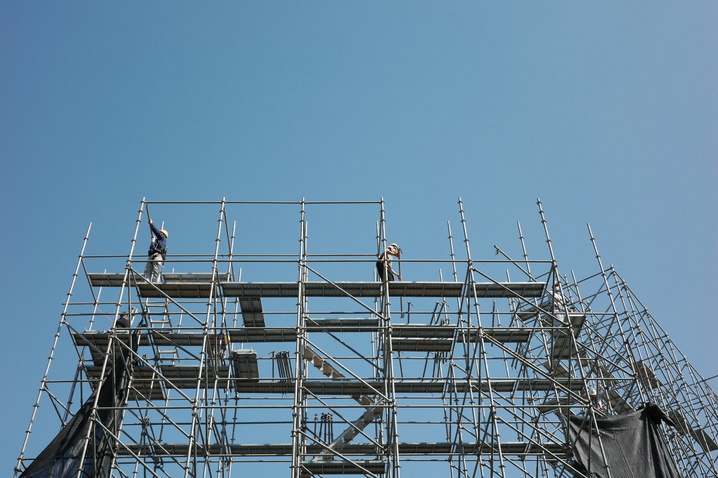 Workers on scaffolding against a clear blue sky
