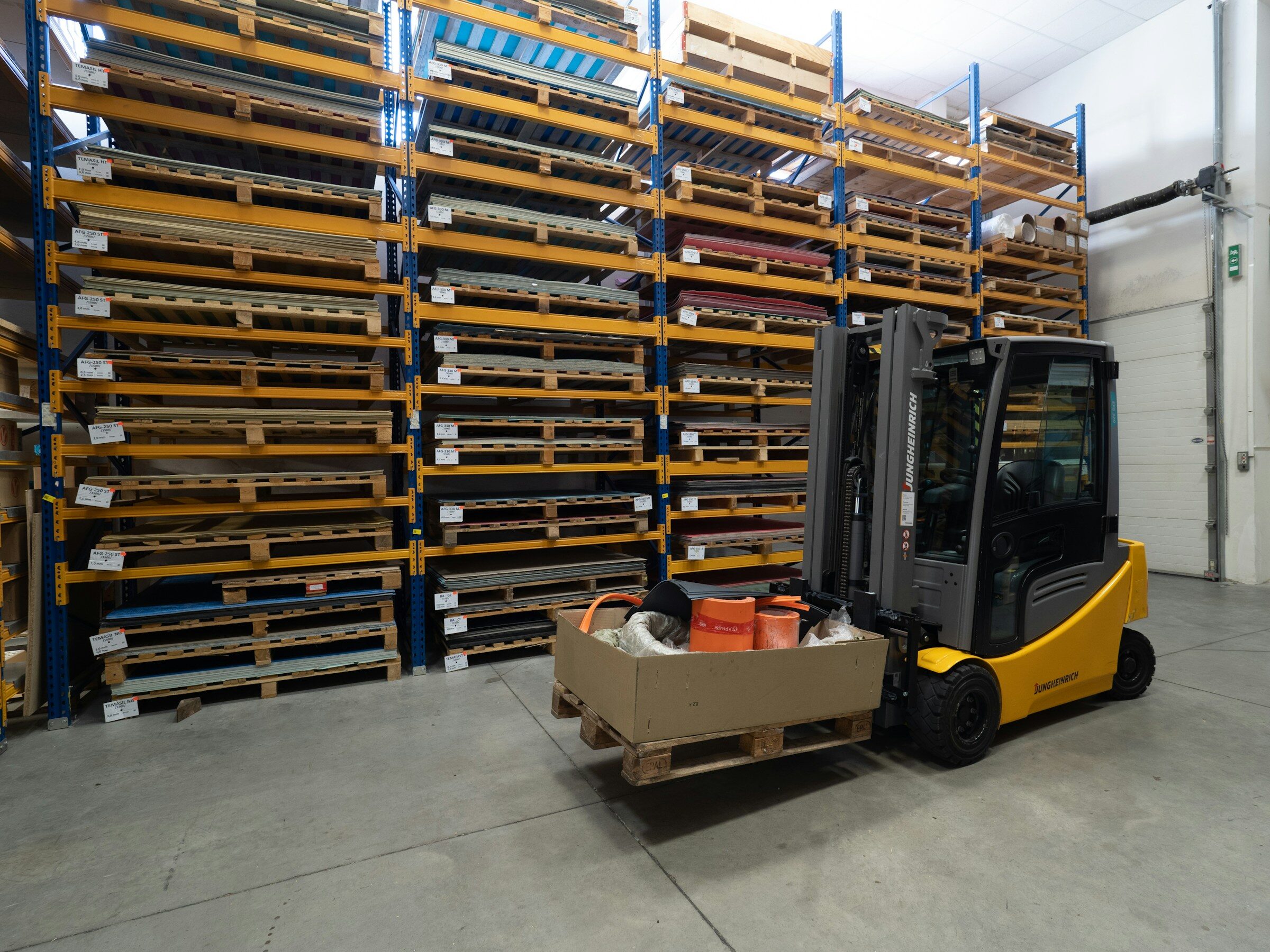 A forklift lifting a box between warehouse racking