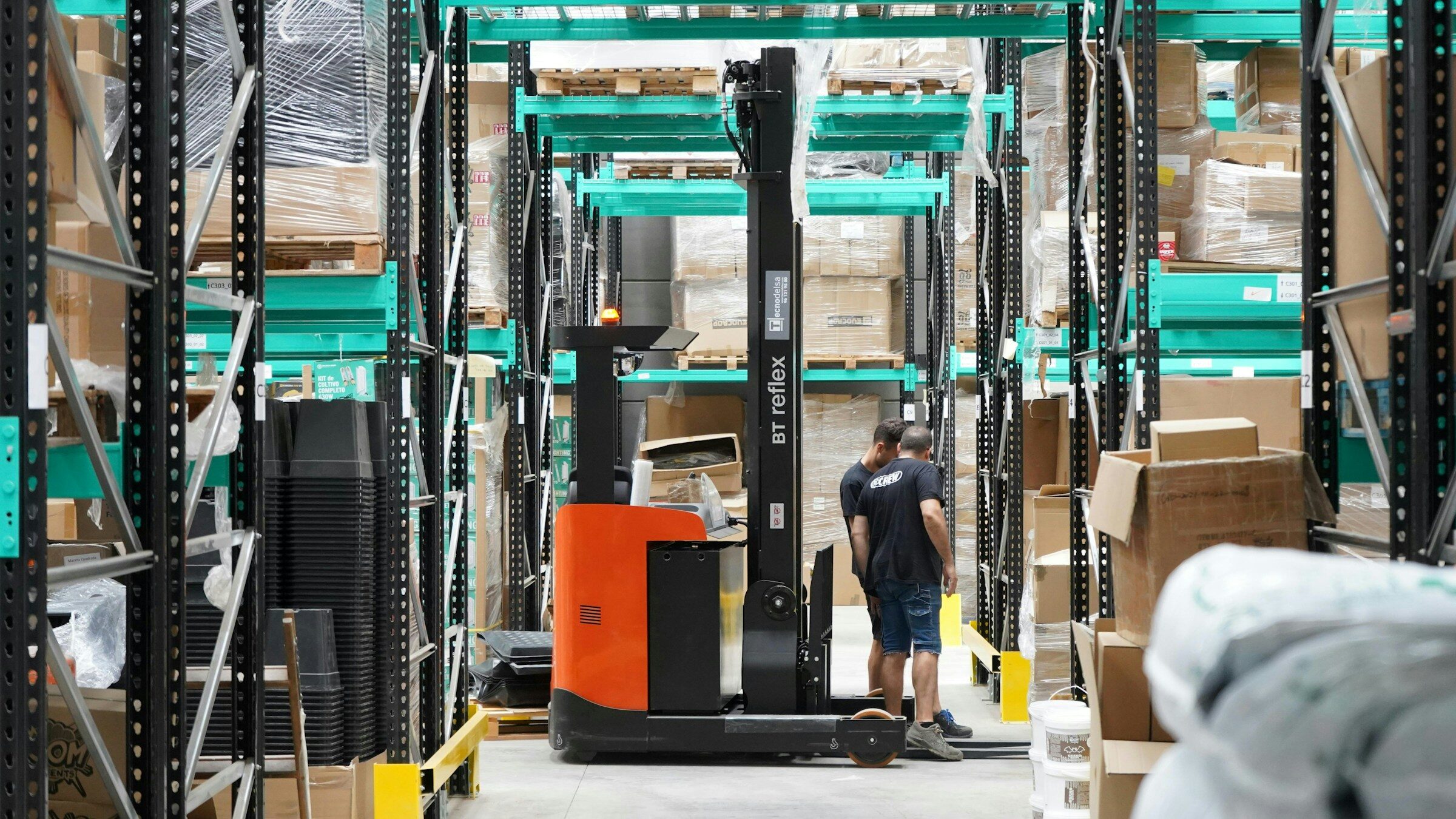 A man standing in a warehouse beside a forklift