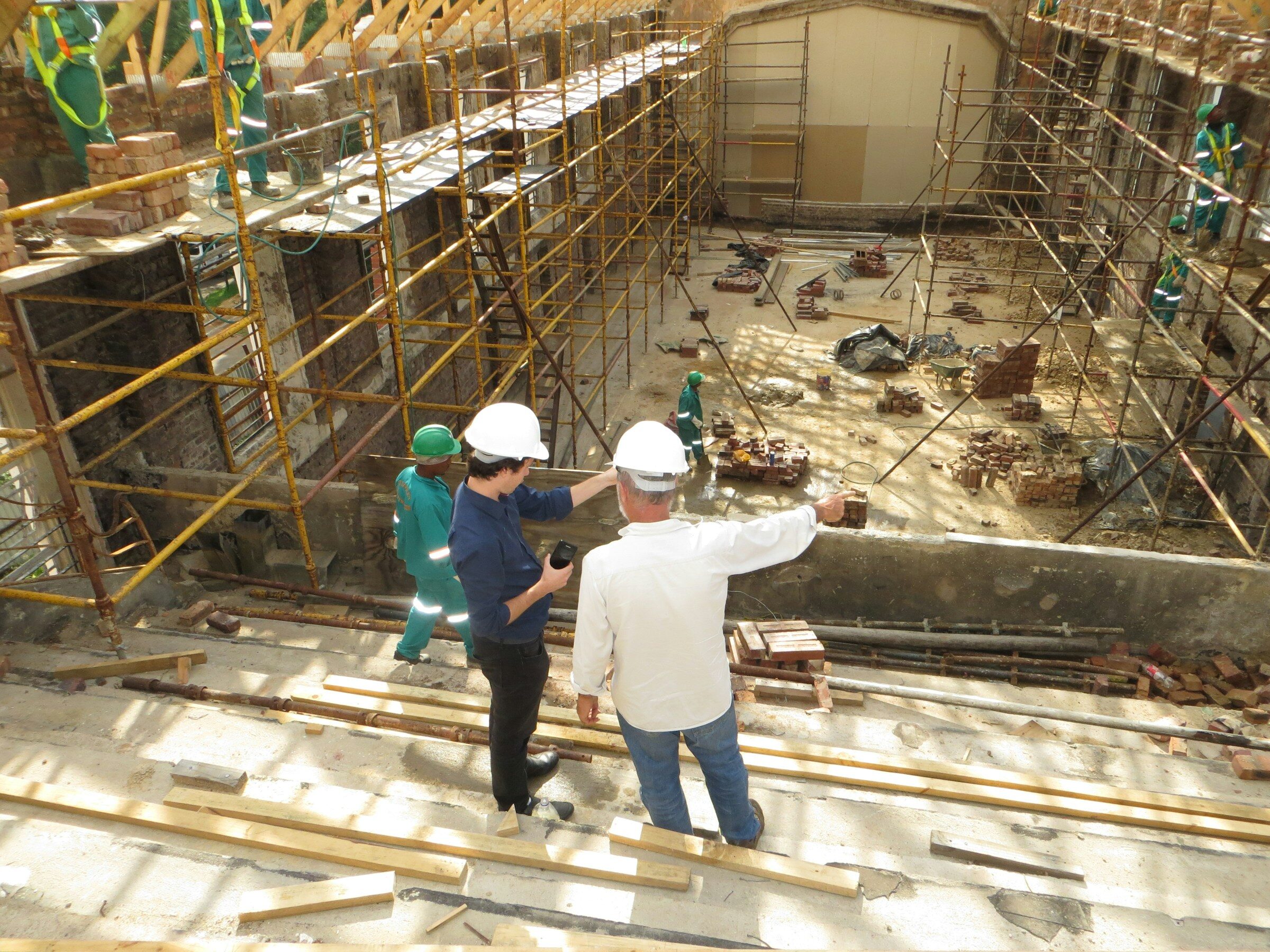 Two workers in hard hats reviewing work on site