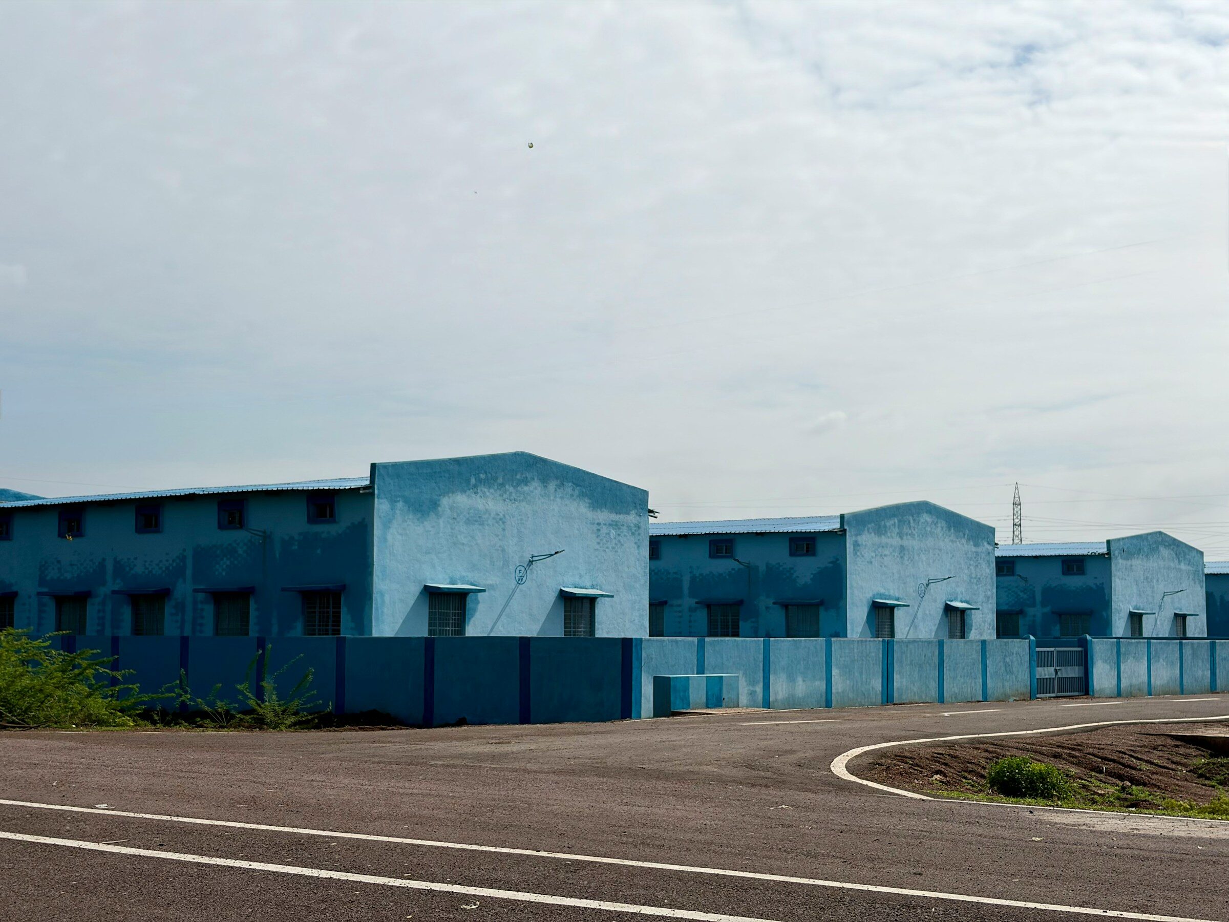 A row of blue industrial buildings along a road