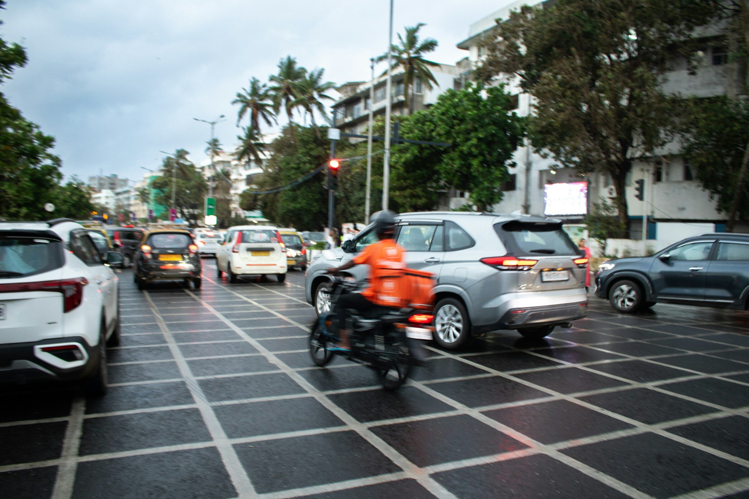 A delivery rider on a motorcycle in city traffic