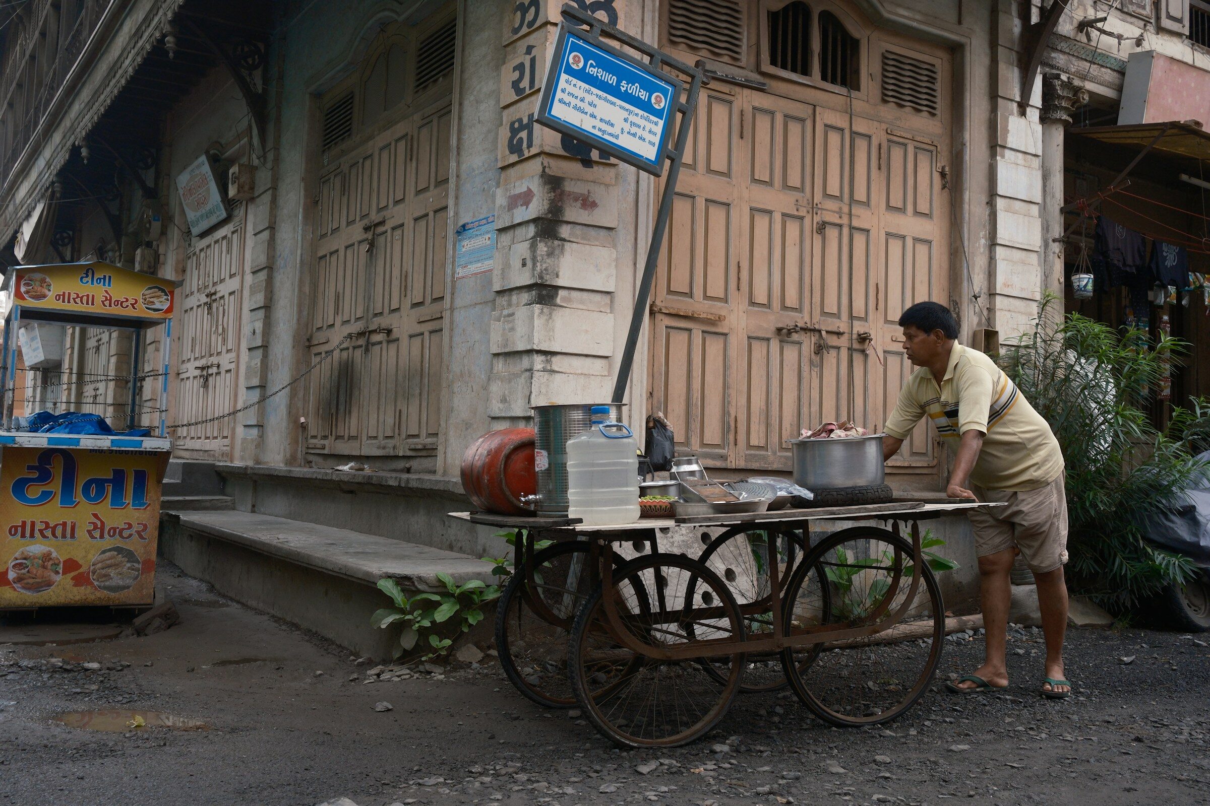 A man cooking at a street food cart beside closed shops