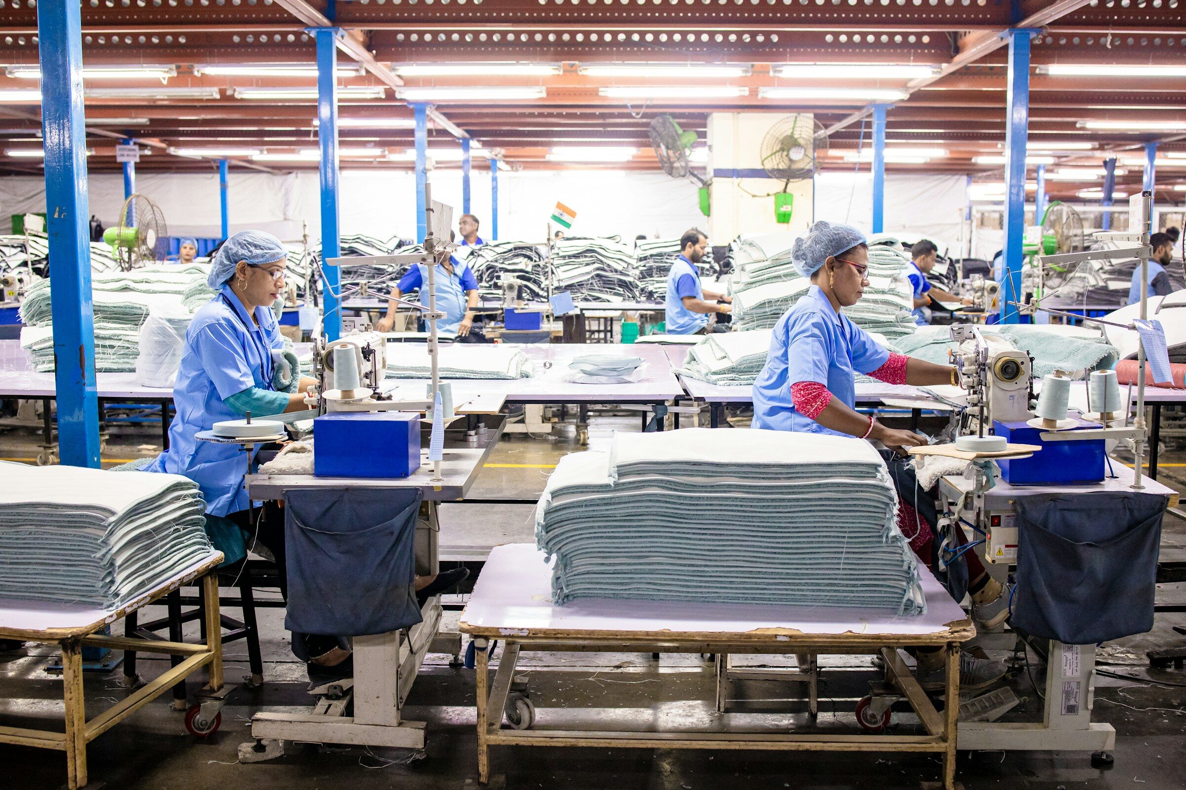 Workers sewing textiles in a large garment factory