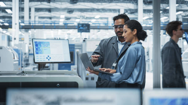 Engineers checking inventory and orders on a laptop in a facility
