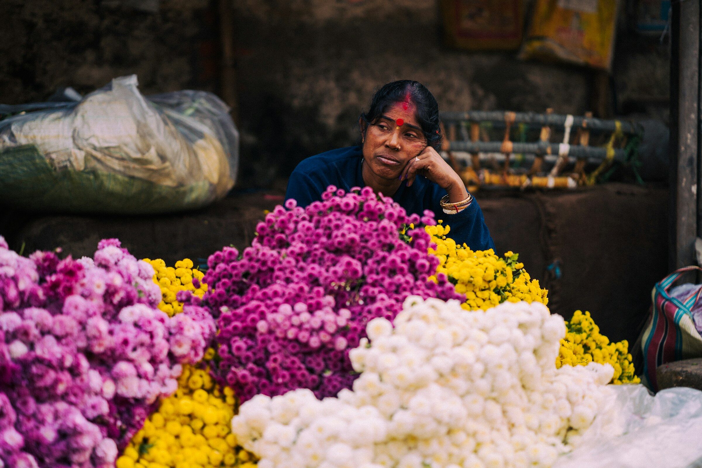 A woman behind a colourful flower display at a Kolkata market