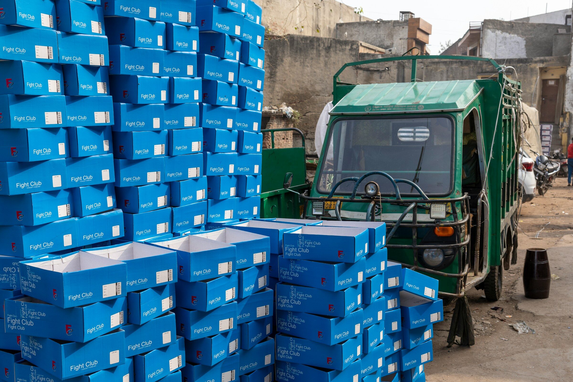 A green goods tempo beside a wall of blue plastic crates