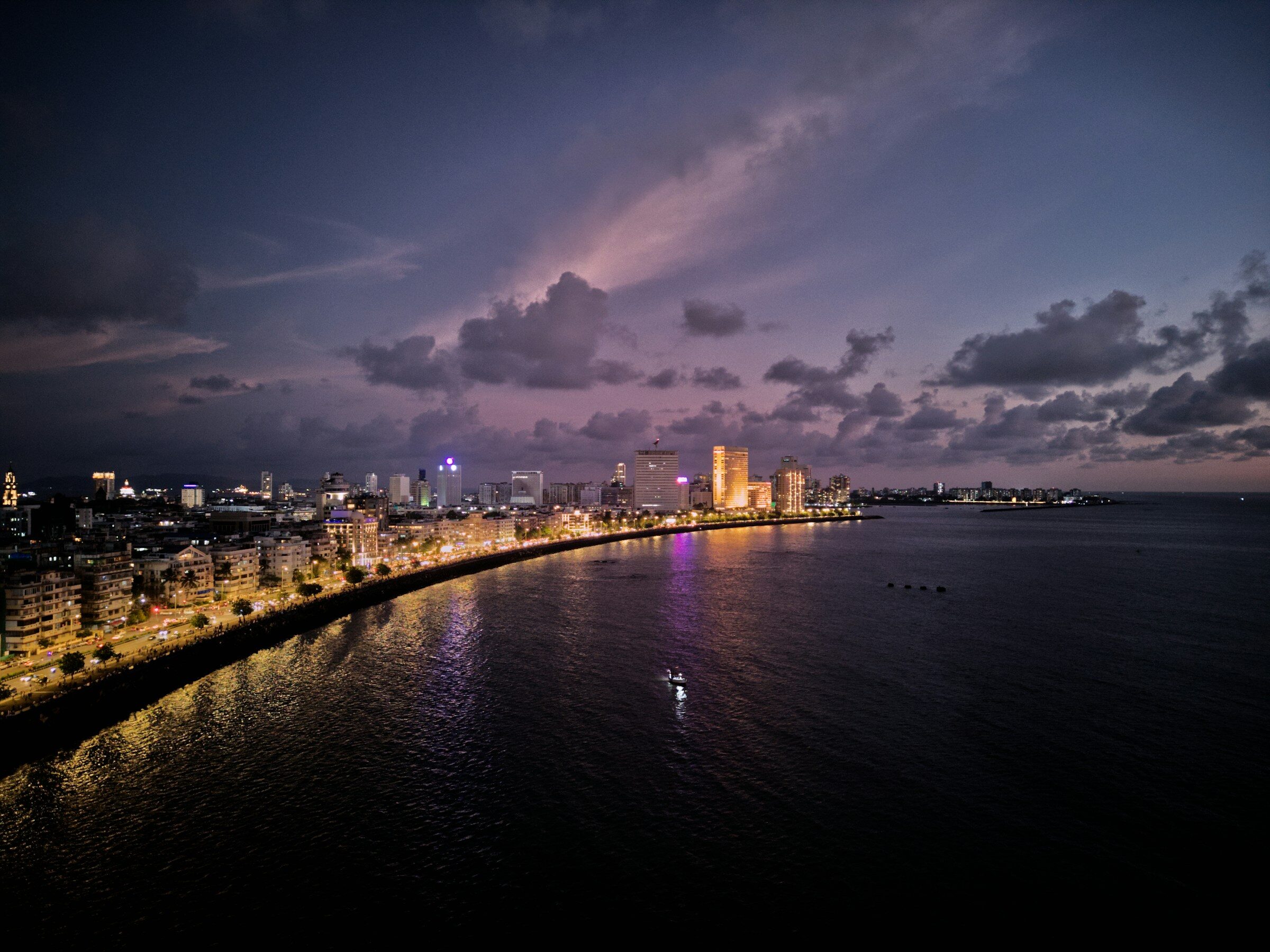 Marine Drive curving along the water at dusk with the Mumbai skyline lit