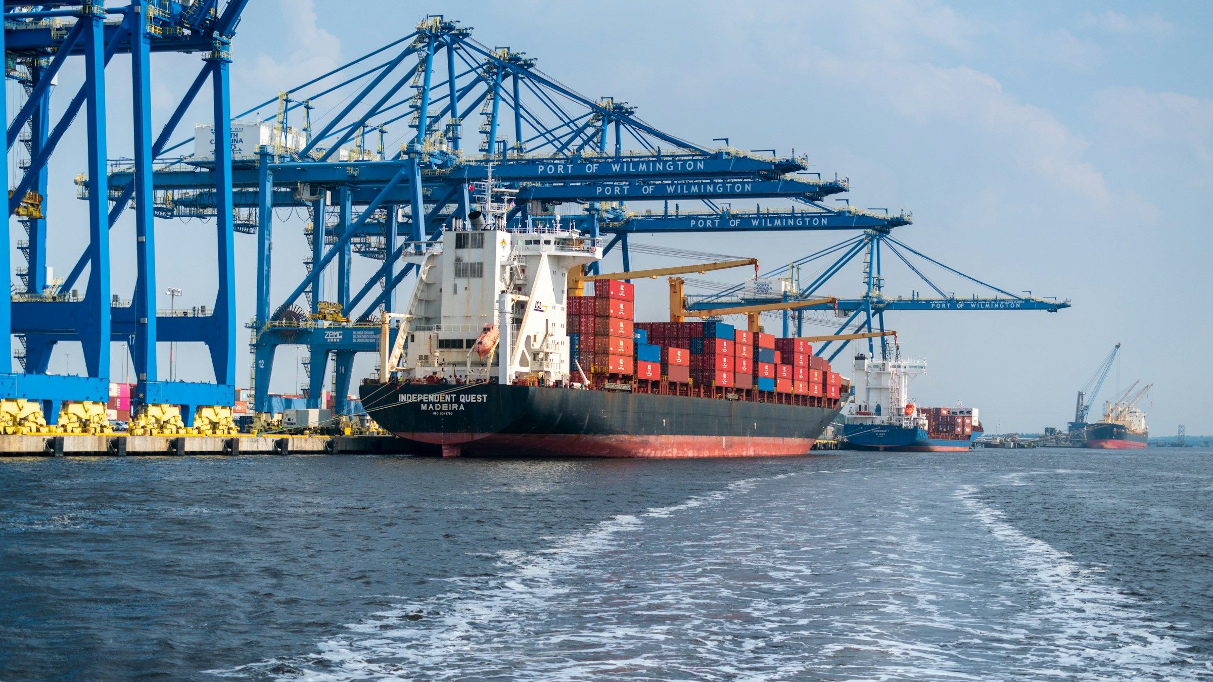 A container ship under blue harbour cranes
