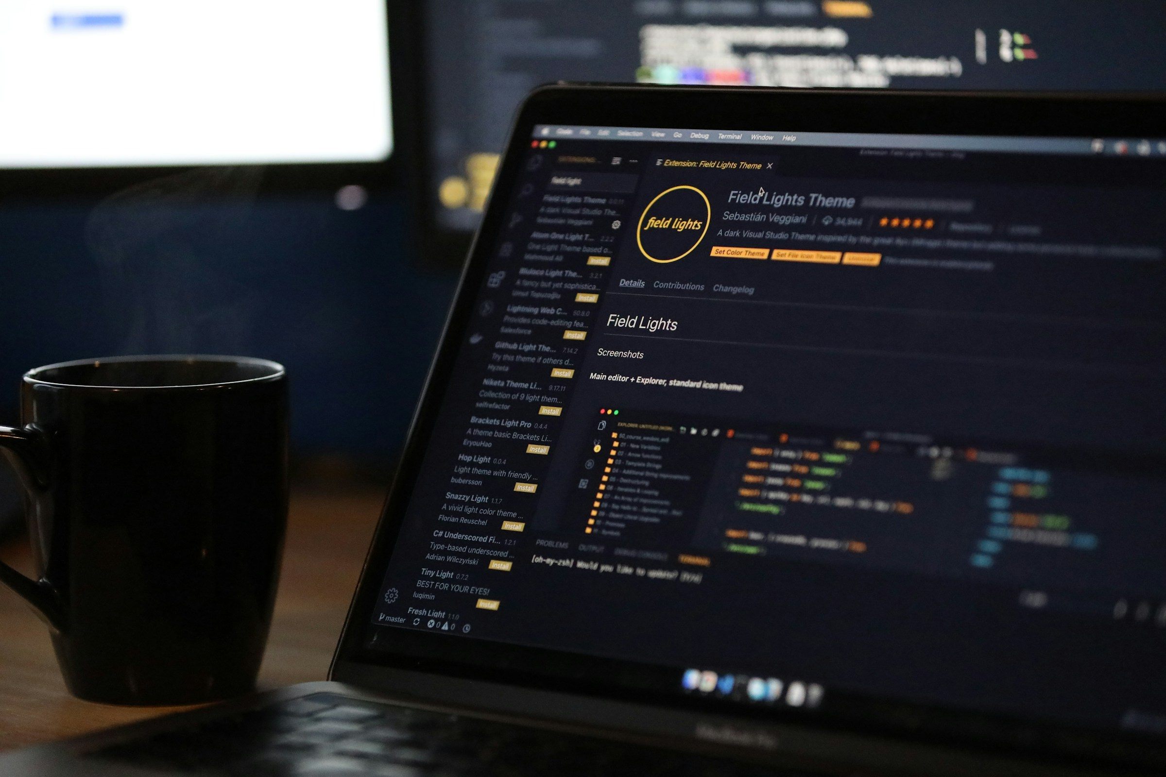 A laptop showing code beside a hot cup of coffee