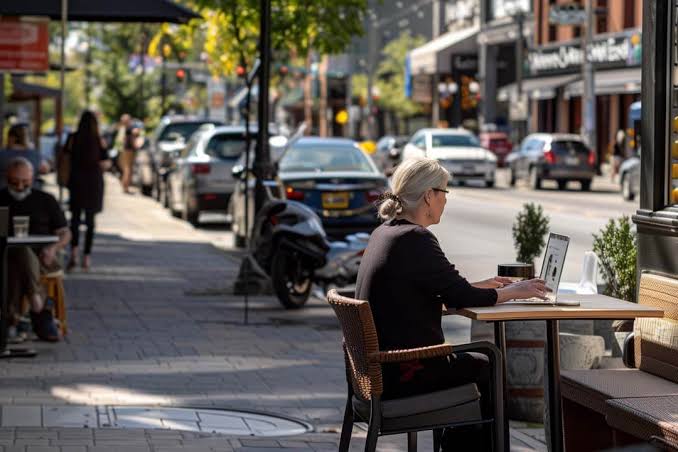 Toronto small business owner working on a laptop at a sidewalk cafe