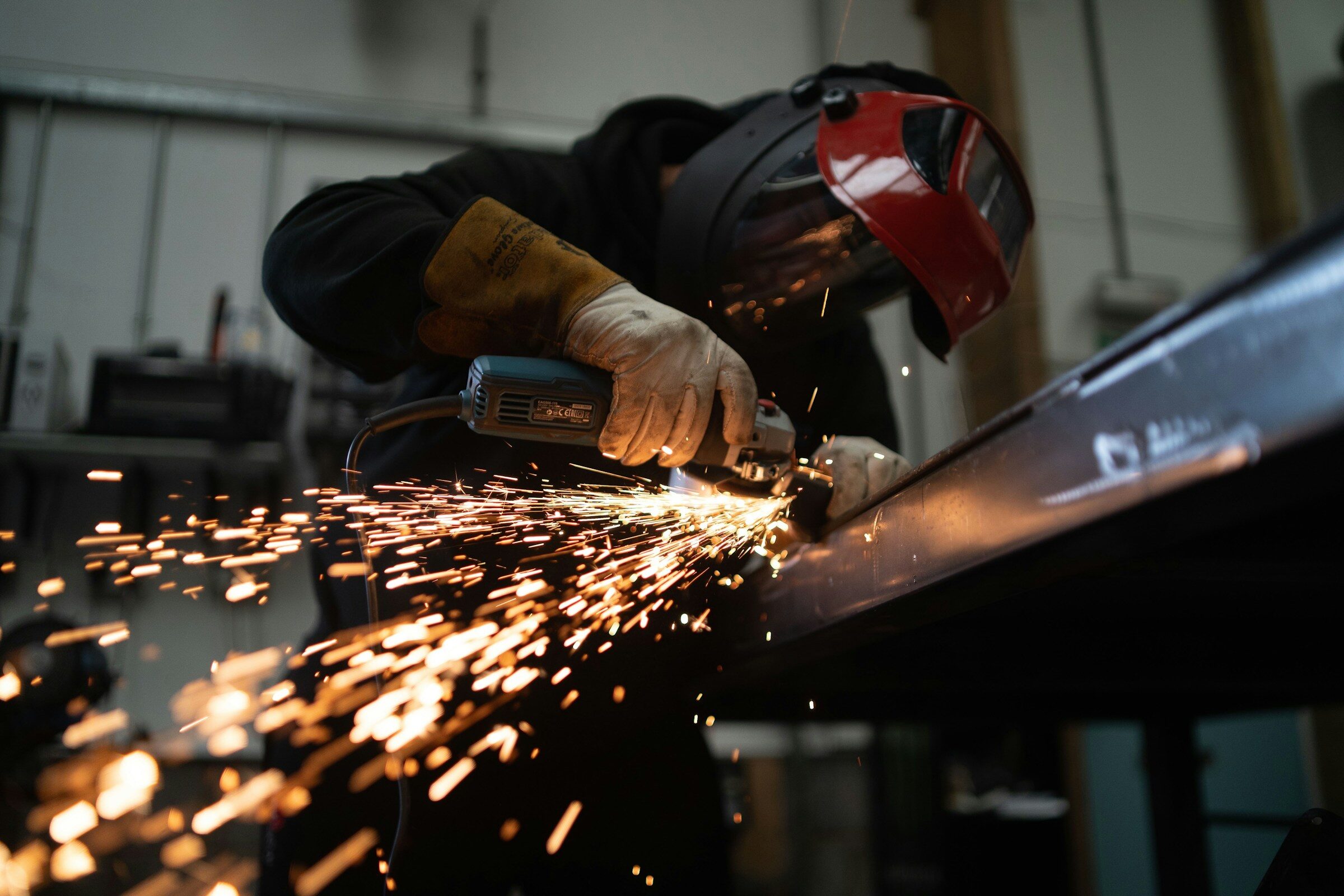 Fabricator grinding a steel beam, sparks flying