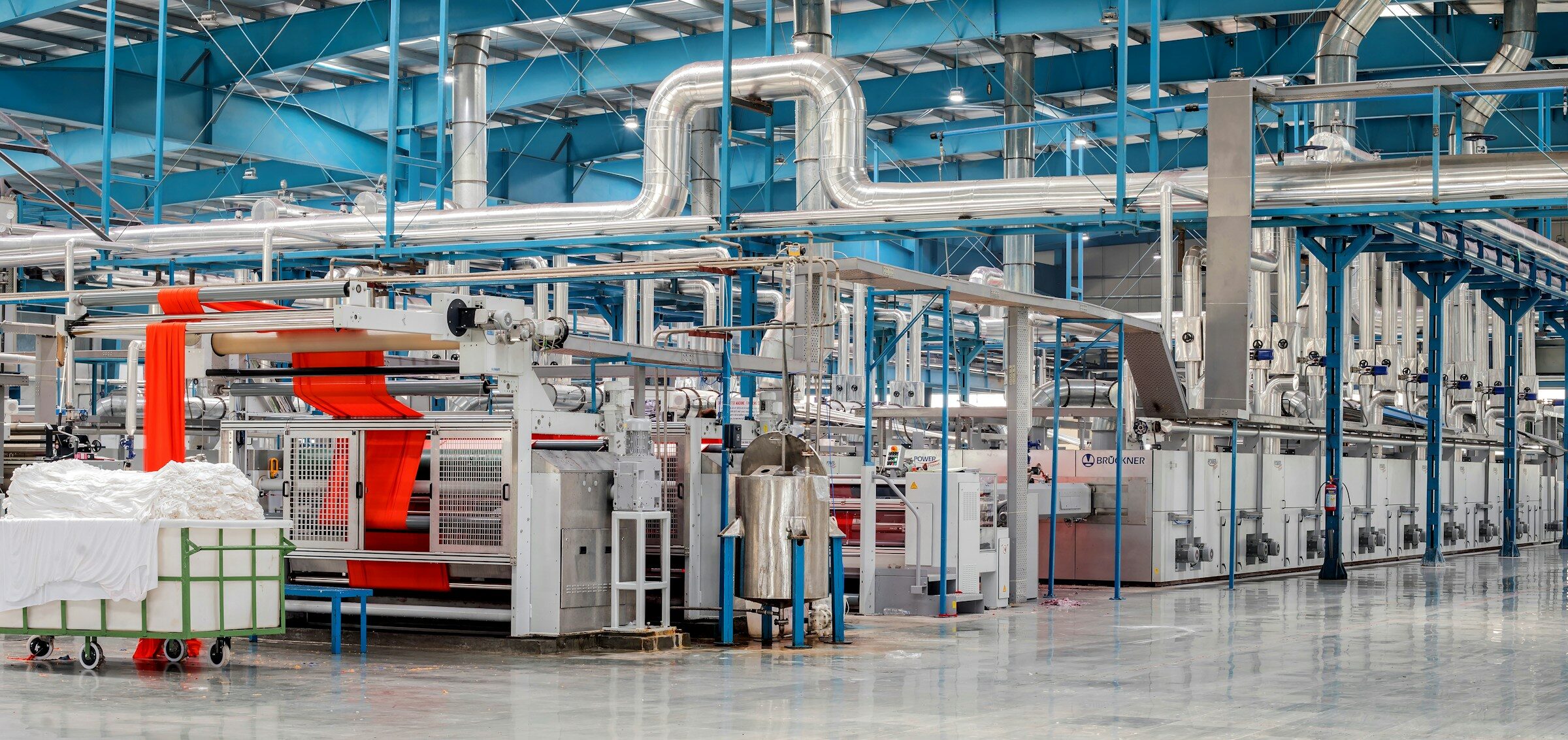 Industrial textile factory floor with machinery and overhead pipework