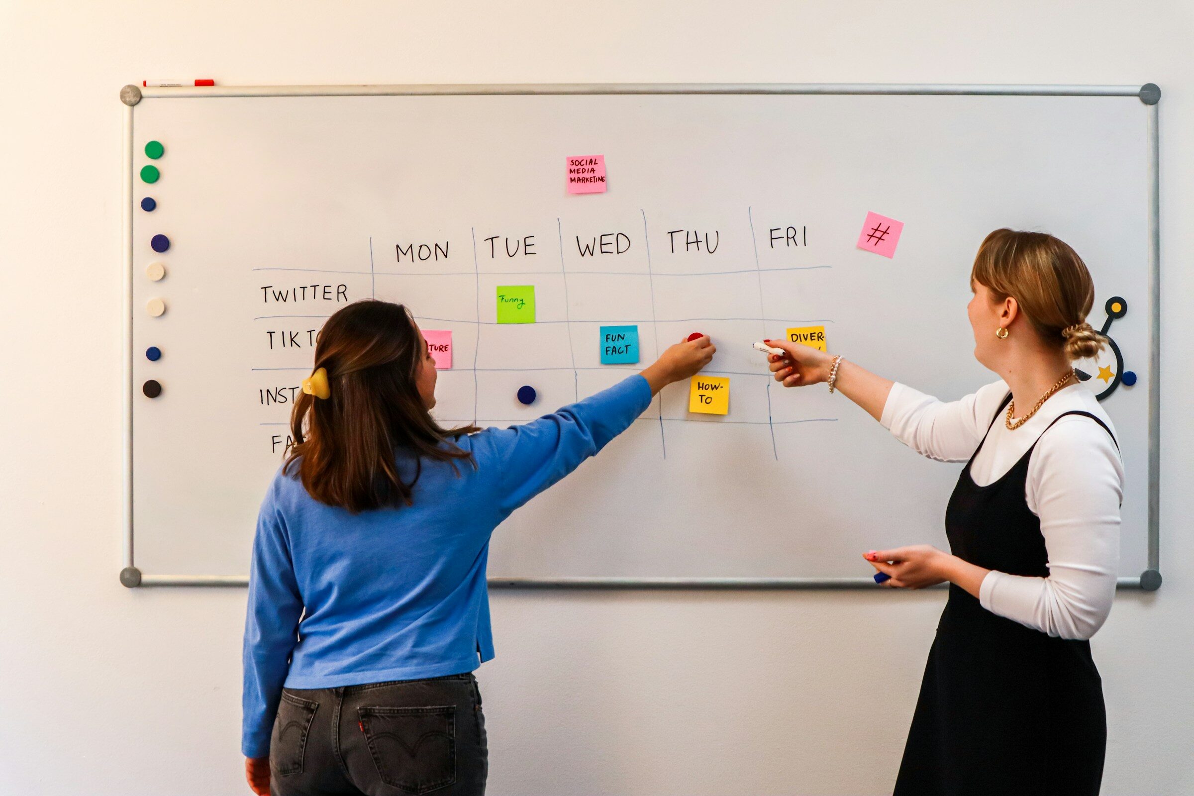 Two colleagues mapping a process on a whiteboard with sticky notes