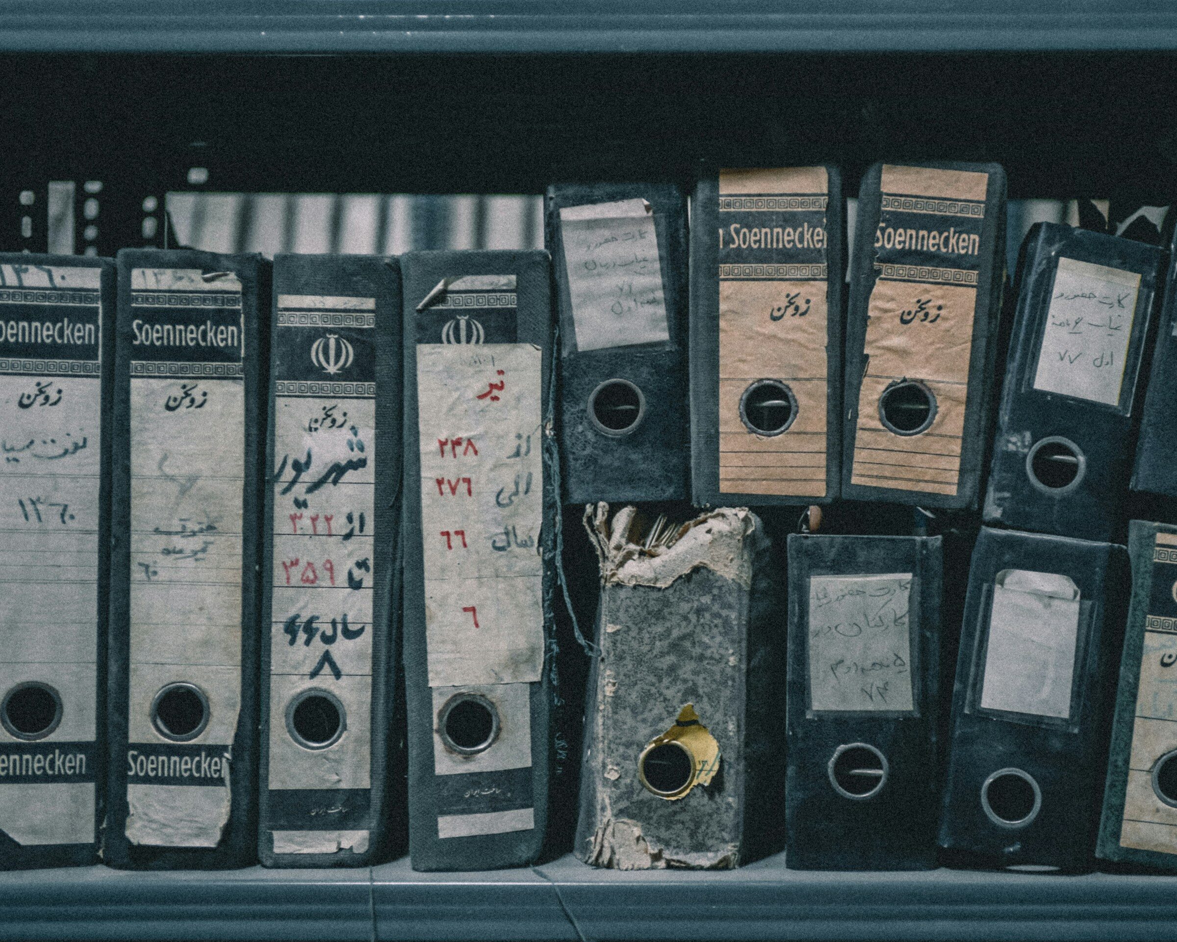 A row of worn binders on a dusty shelf
