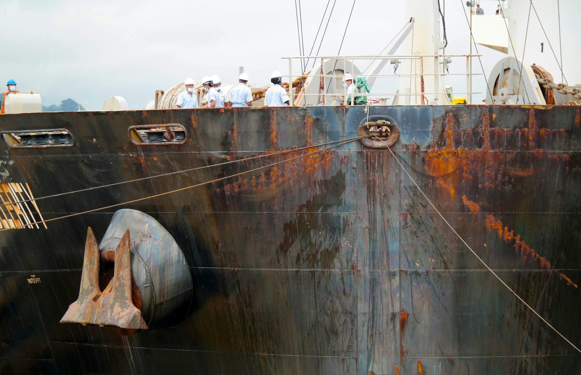 Weathered steel plates and an anchor on the side of a large ship