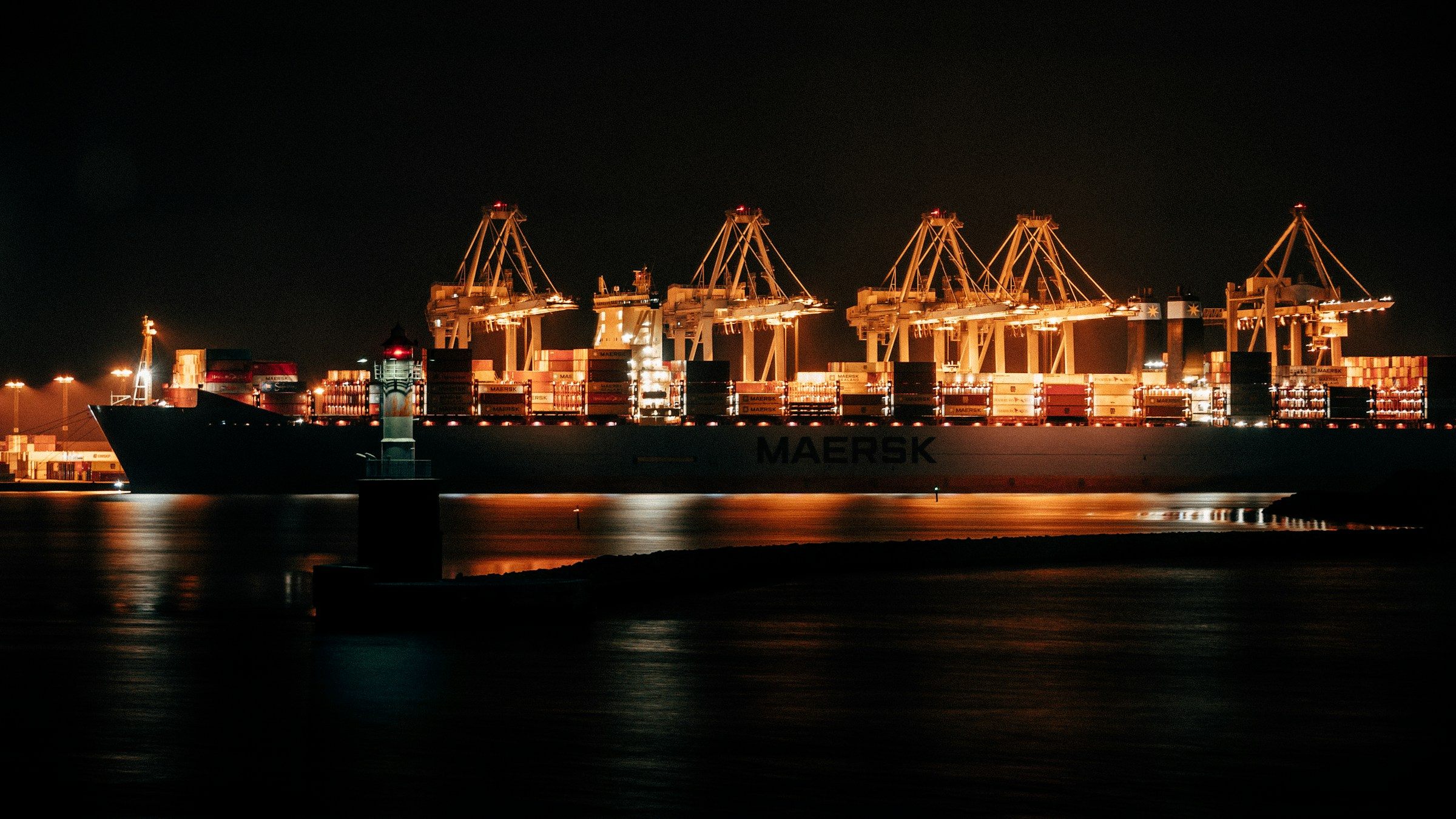 A cargo ship at a lit dock at night