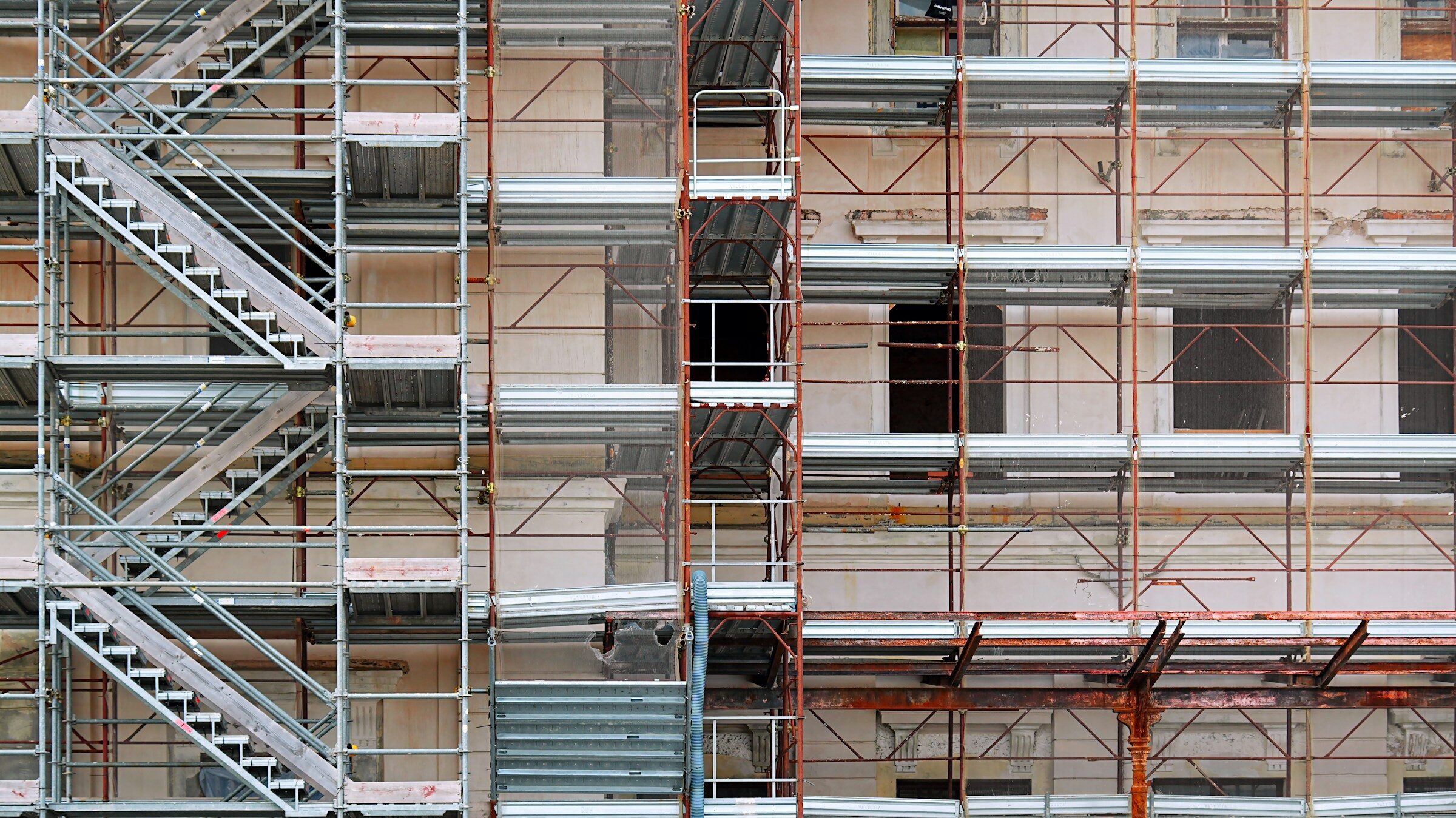 A building being rebuilt behind scaffolding while it stays standing