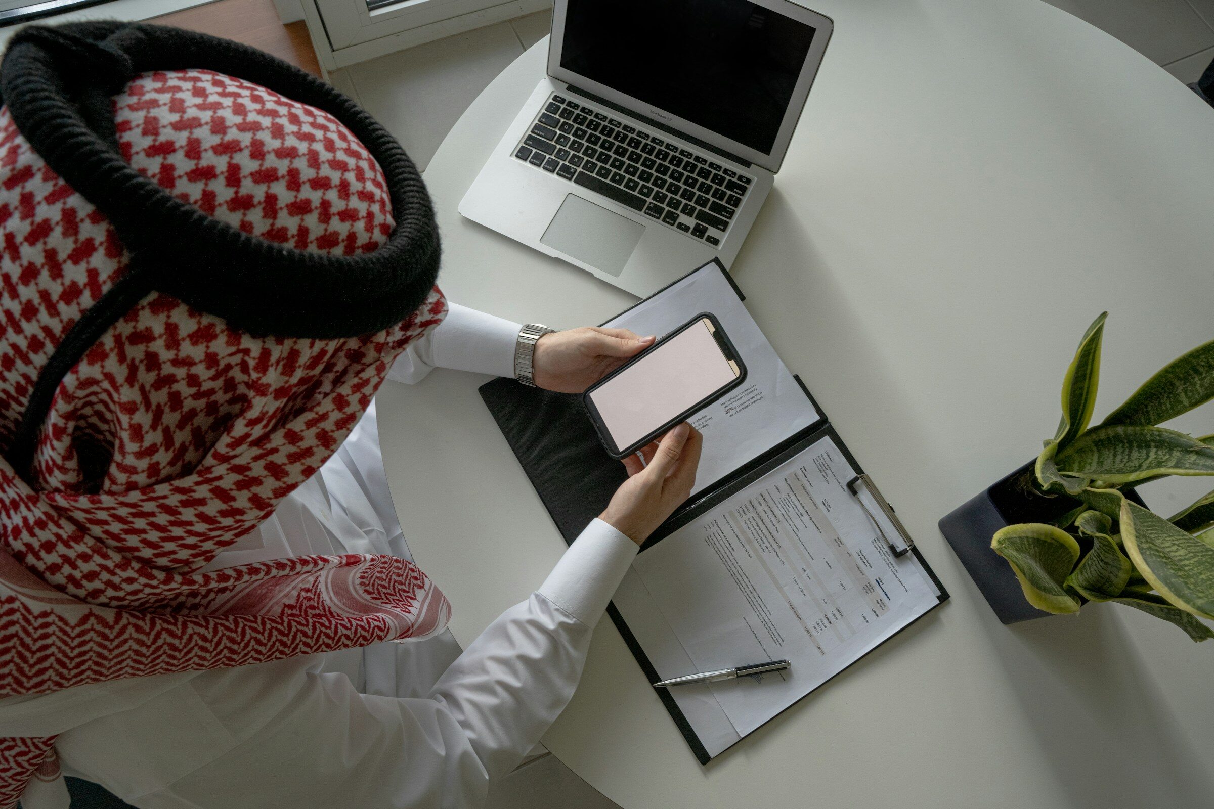A desk with a laptop and a clipboard of notes